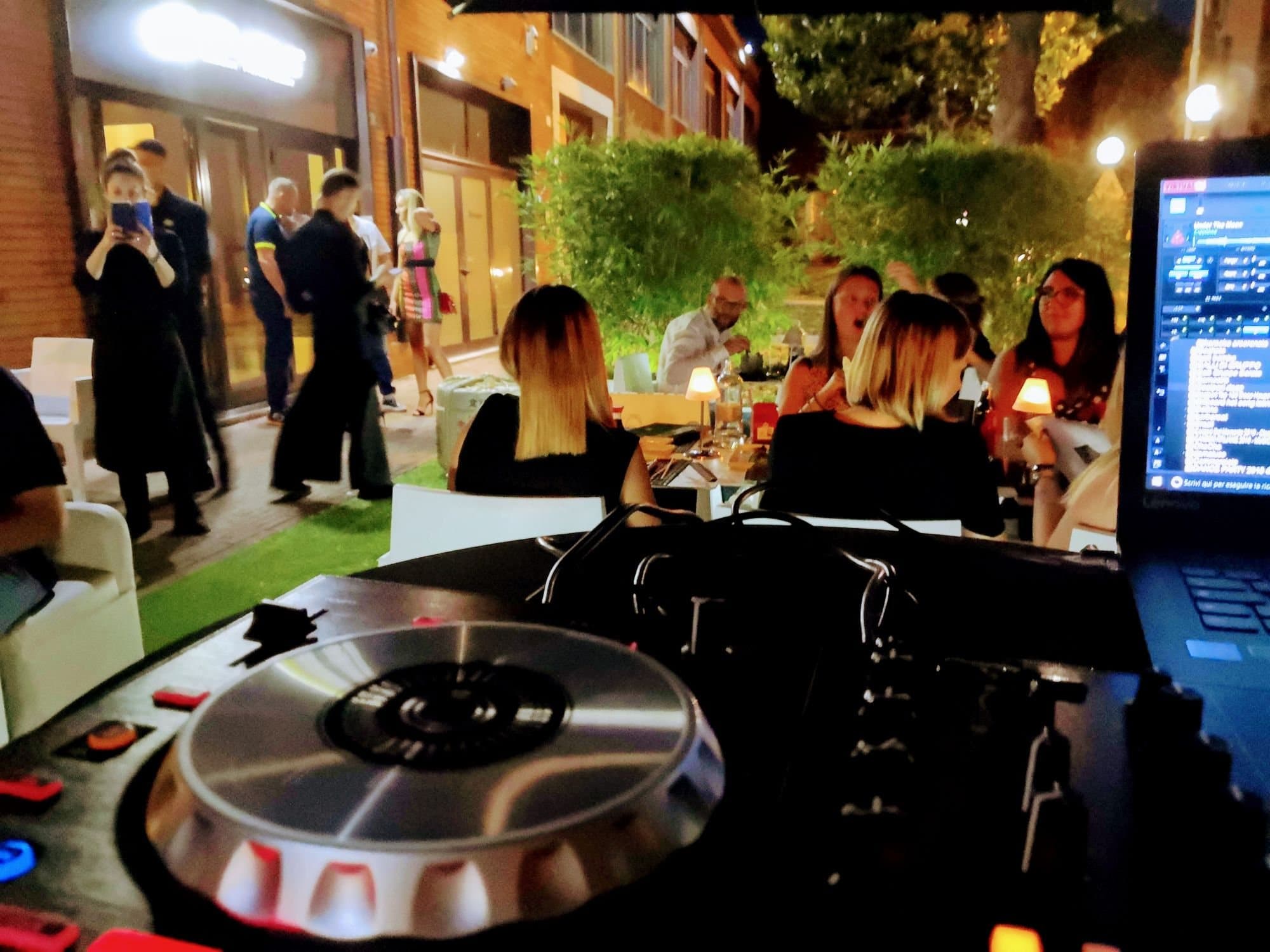Cena in terrazza tra le luci sospese e la consolle